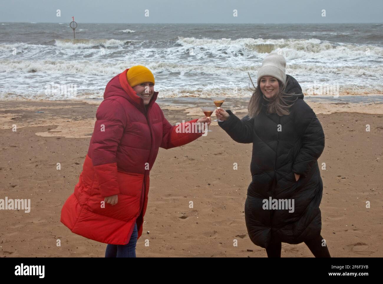 Portobello, Édimbourg, Écosse, météo britannique. 31 mars 2021. L'après-midi de tempête avec une température de 6 degrés centigrade et des mers rugueuses sur le Firth of Forth pour Robyn (Red Coat) qui célèbre aujourd'hui son 39e anniversaire sur la plage avec sa meilleure amie Emma. Ils seraient normalement dans un restaurant mais pas encore possible en raison des restrictions Covid -19. Banque D'Images