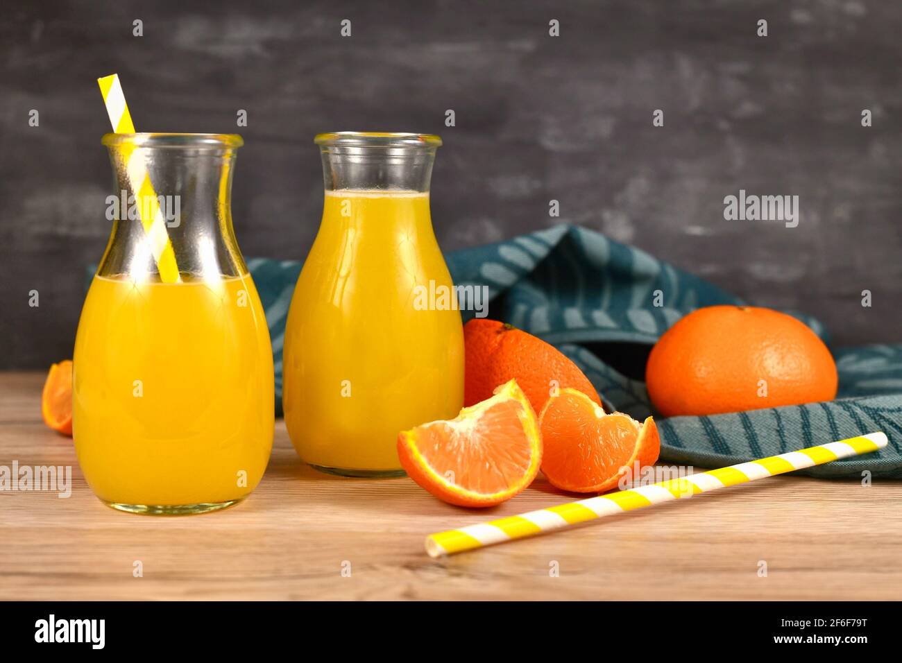Limonade à base d'agrumes dans de petits pots en bouteille avec boire des pailles et des tranches de fruits sur une table en bois Banque D'Images