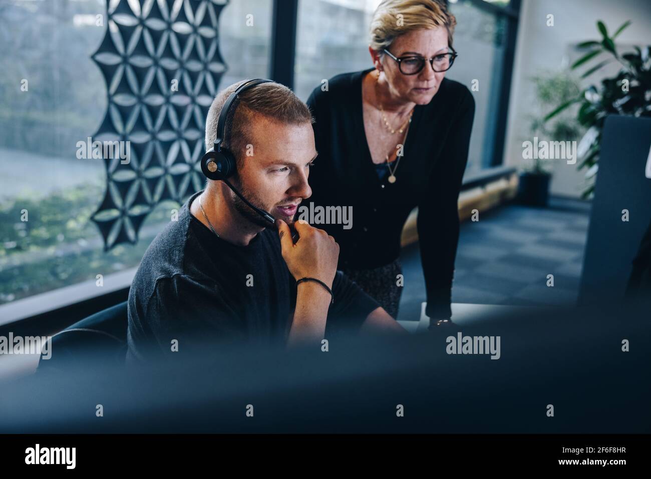 homme d'affaires portant casque regardant l'ordinateur et pensant avec le gestionnaire féminin en plus. Représentant du service clientèle au travail avec le responsable. Banque D'Images