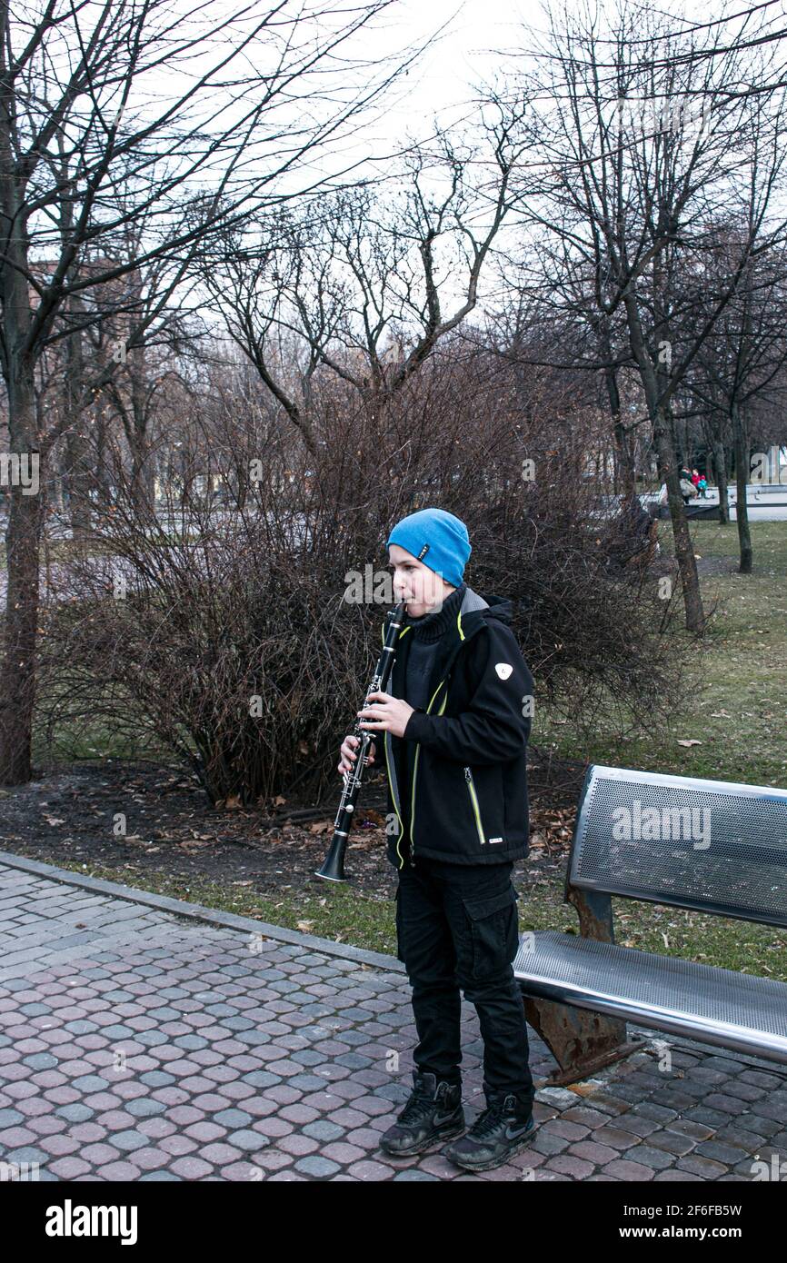Dnepropetrovsk, Ukraine - 03.29.2021: Un garçon dans le parc joue la clarinette. L'enfant est de bonne humeur. Banque D'Images