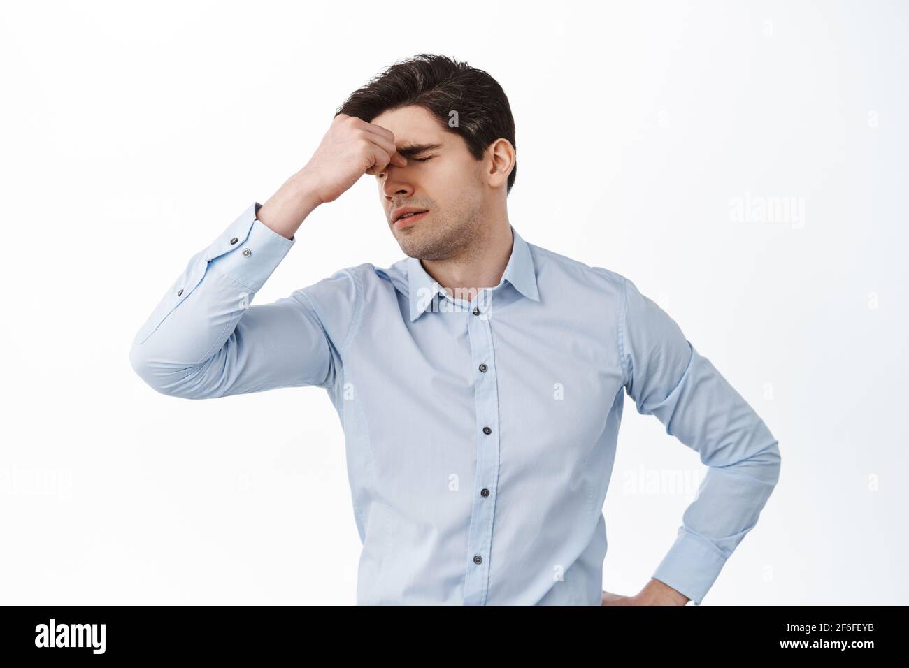 Employé de bureau fatigué, se frottant les yeux fermés après avoir travaillé avec l'ordinateur, homme d'affaires se sentant fatigue pendant le travail, affligé après le travail excessif, debout Banque D'Images