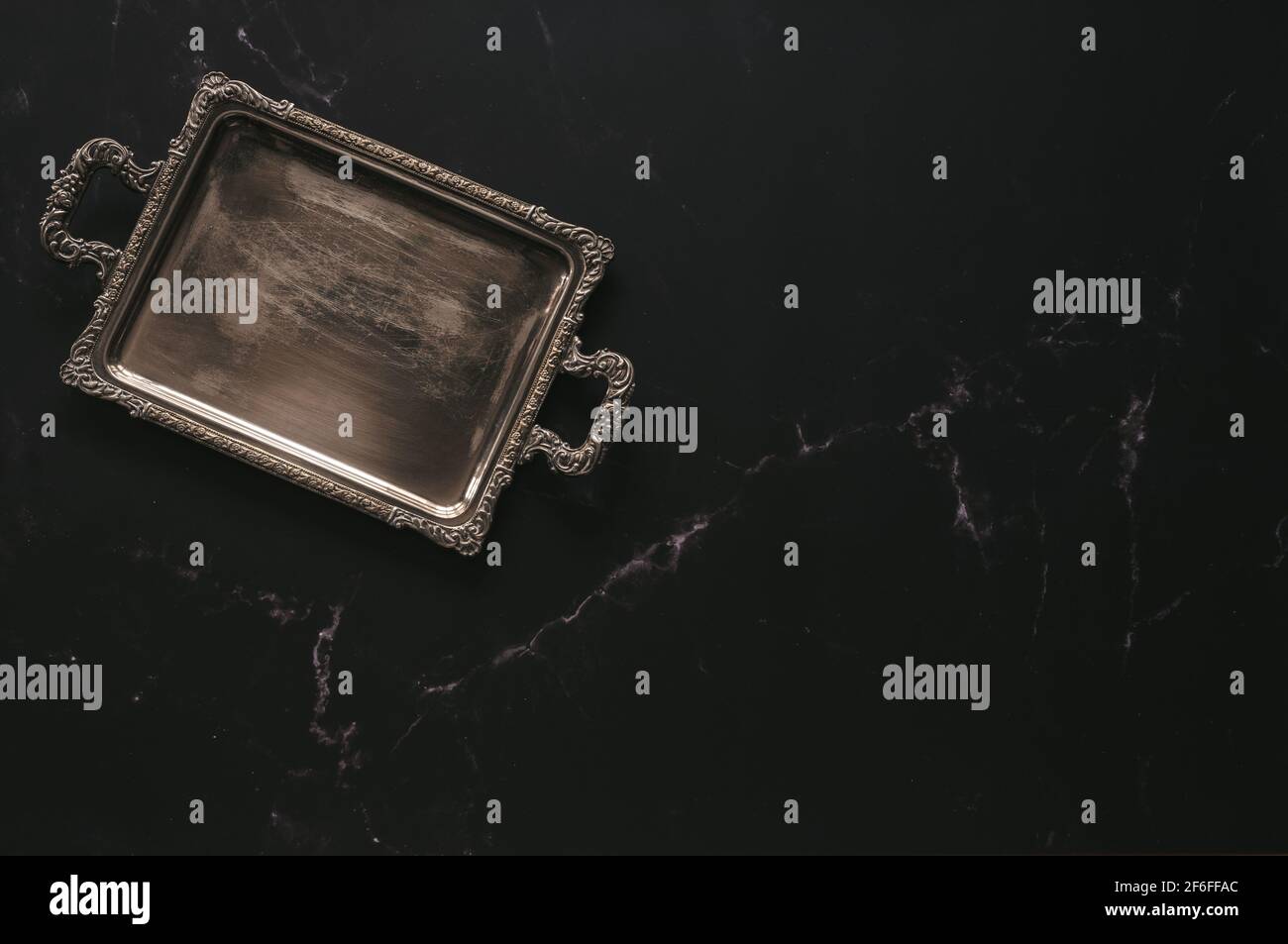Pose plate d'un plateau d'argent antique vide contre foncé marbre Banque D'Images