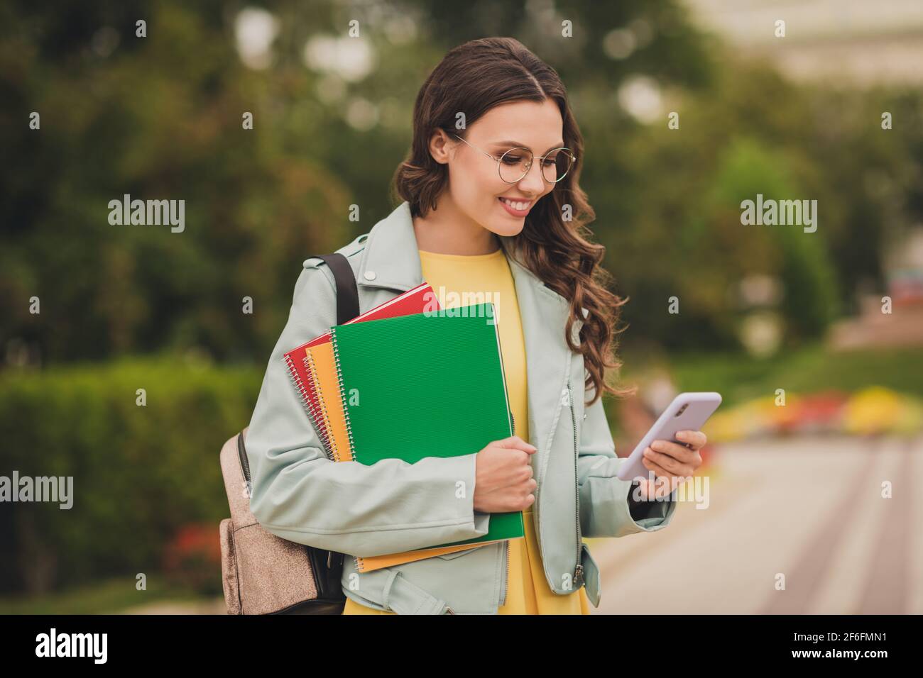 Photo de joli positif personne porte sac à dos tenir livre carnet regardez le téléphone écrire un billet de blog à l'extérieur Banque D'Images