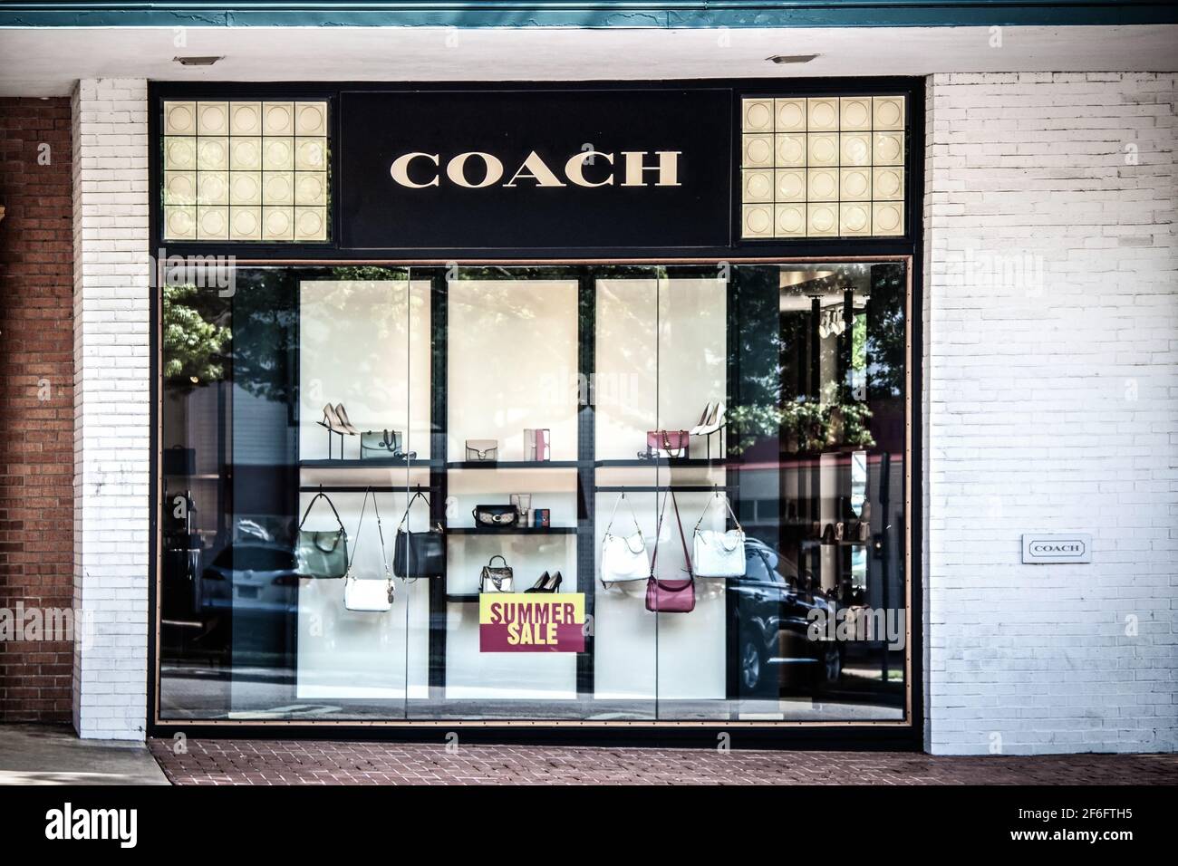2020 07 14 Tulsa USA - Afficher la fenêtre de la boutique Coach avec l'été Panneau de vente et réflexions de voitures et d'arbres Banque D'Images