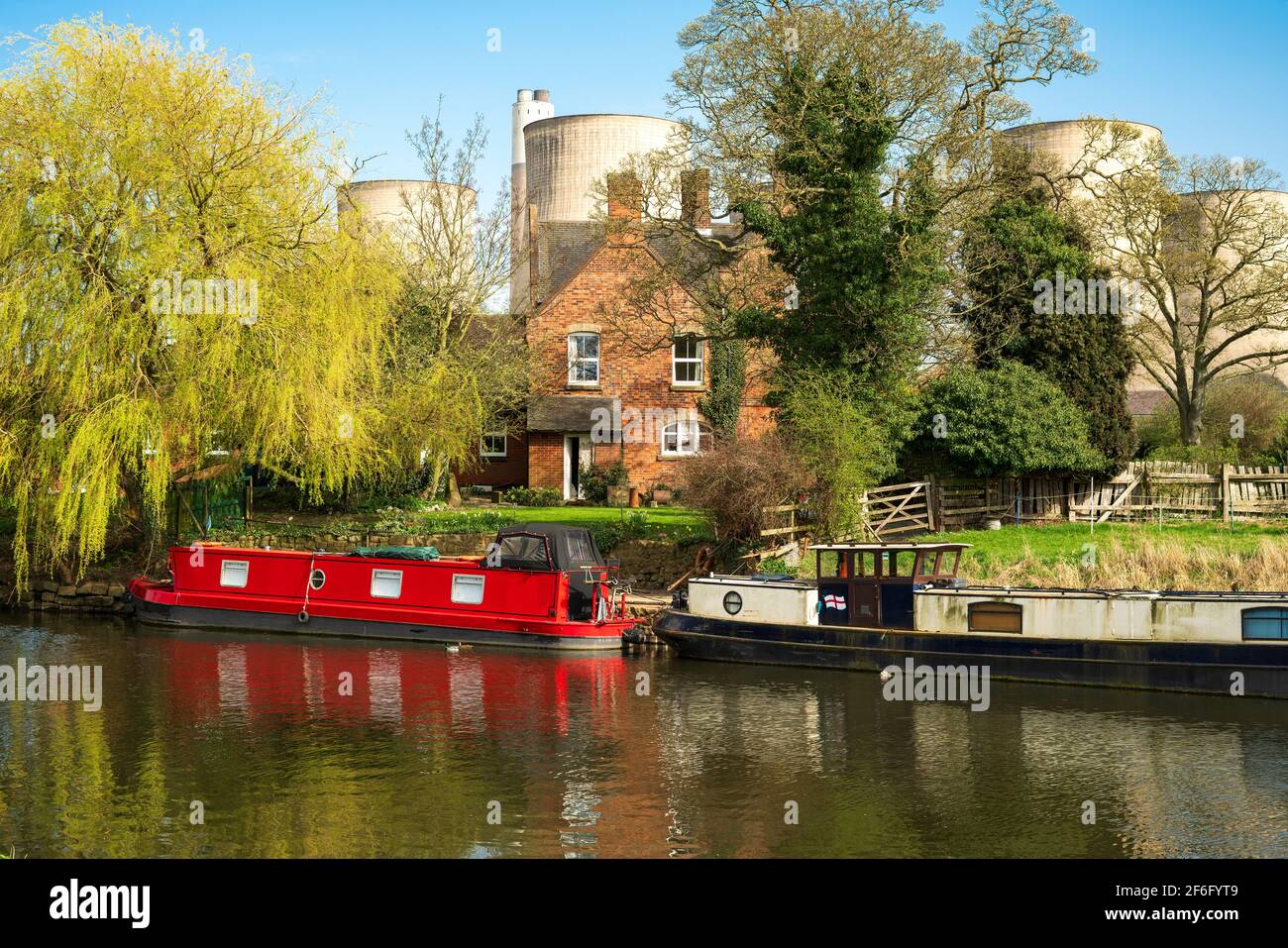 Des bateaux étroits amarrés sur une rivière à côté d'une grande maison Banque D'Images