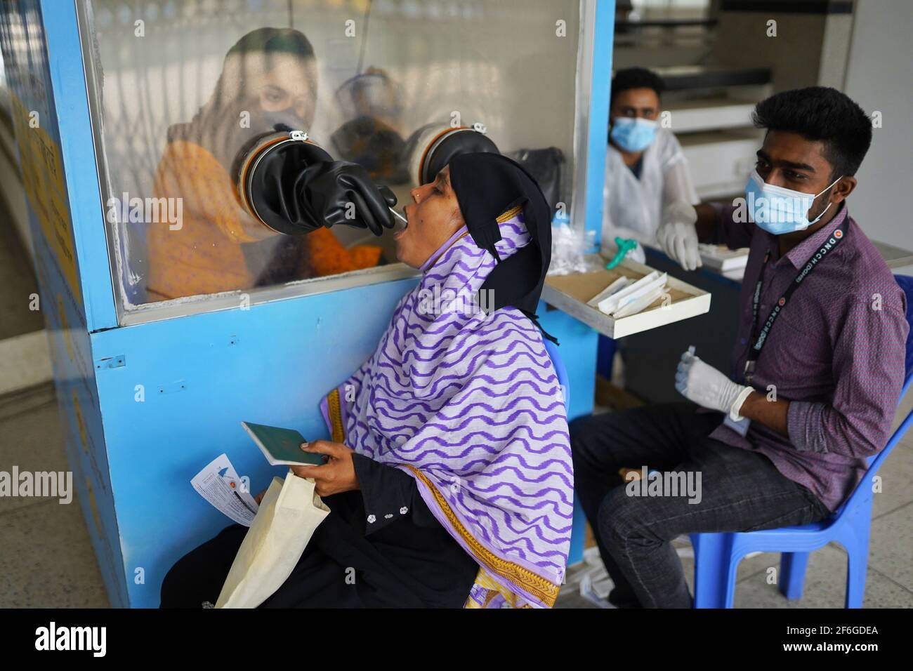 Une femme immigrée est titulaire d'un passeport bangladais tout en donnant un échantillon pour le test obligatoire du covid-19 avant de quitter le pays.selon l'Organisation internationale pour les migrations (OIM), plus de 1.2 millions de travailleurs migrants du Bangladesh travaillent dans le Royaume d'Arabie saoudite et dans d'autres pays du Moyen-Orient. La plupart des femmes migrantes sont employées comme travailleuses domestiques migrantes (MDW). D'avril à octobre 2020, un total de 20,788 femmes migrantes sont retournées au Bangladesh par l'aéroport international Hazrat Shahjalal de Dhaka. Banque D'Images