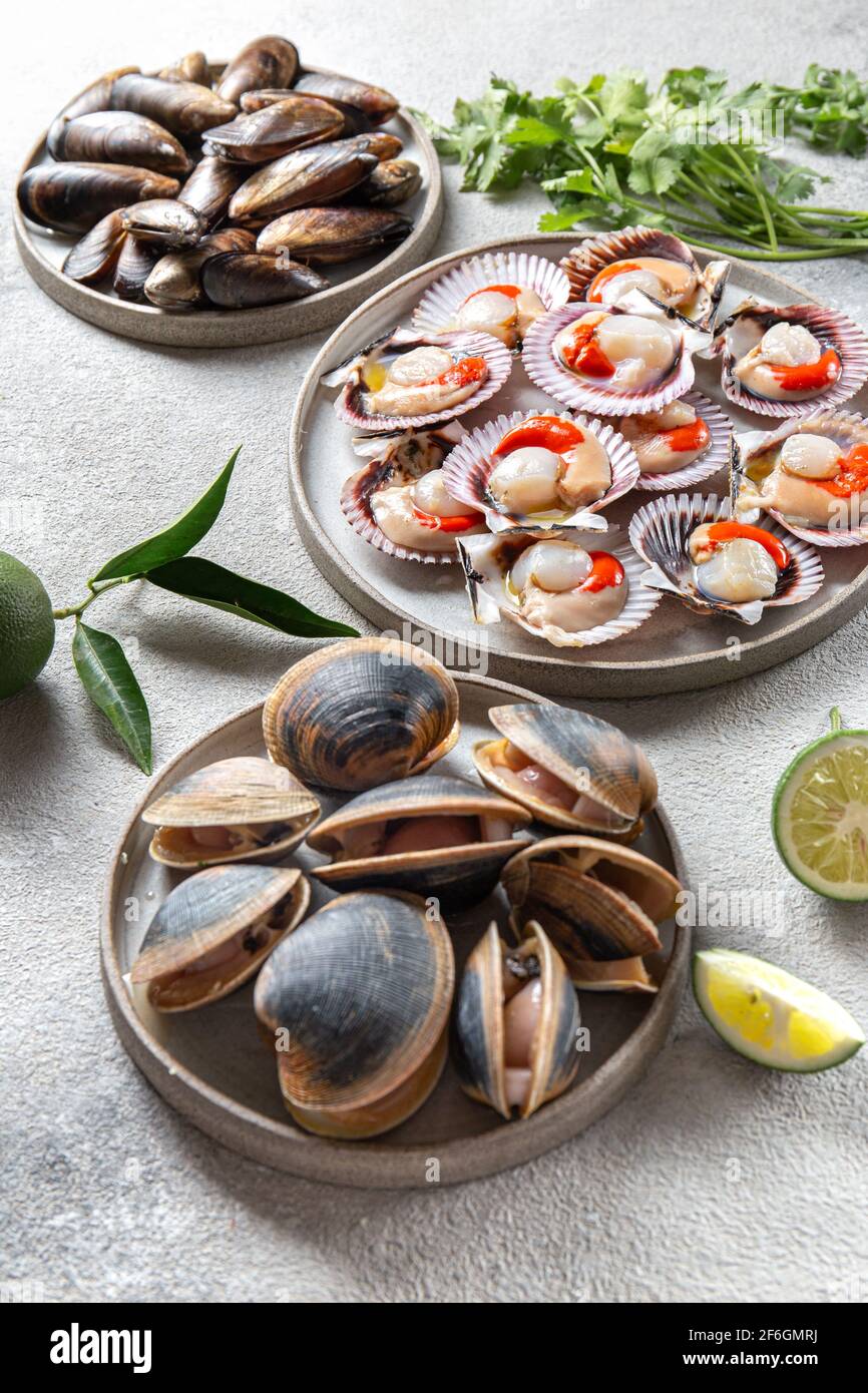 Palourdes, moules et pétoncles de fruits de mer sur des assiettes grises Banque D'Images