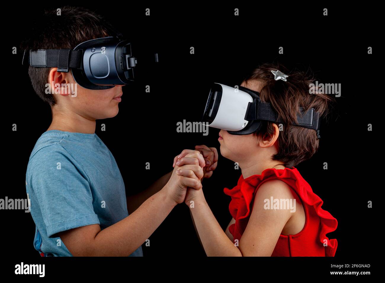 Un garçon caucasien et une fille portant des casques de réalité virtuelle jouent à un jeu multijoueur. Un concept futuriste avec des enfants dans une dimension différente Banque D'Images