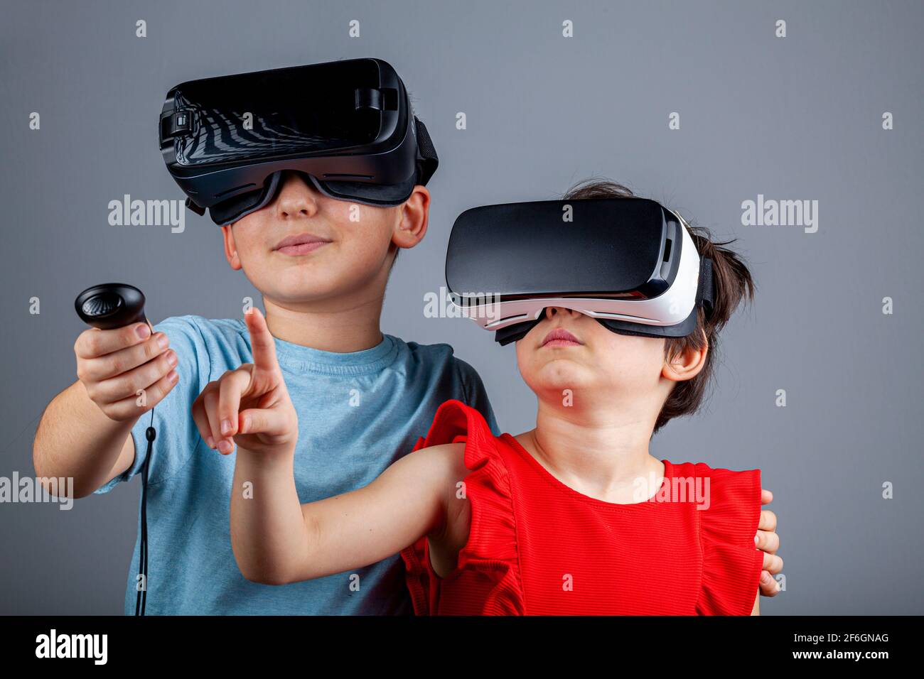 Un garçon caucasien et une fille portant des casques de réalité virtuelle jouent à un jeu multijoueur. Un concept futuriste avec des enfants dans une dimension différente Banque D'Images