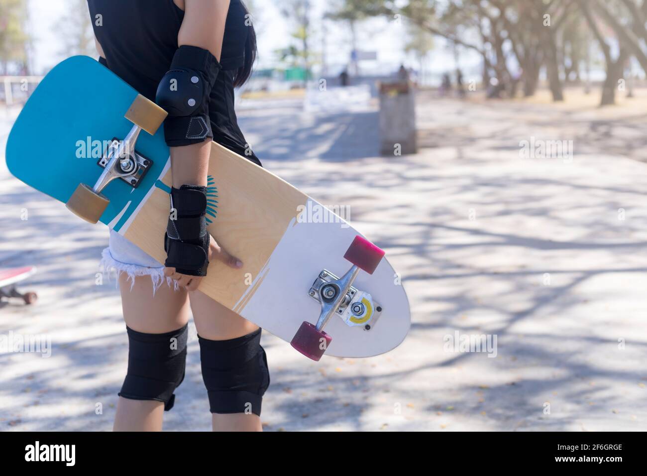 Gros plan sur les jeunes femmes porter une protection et tenir la main  skateboard, surf skate sur fond de parc public de rampe de skate. Libre  relax skate surf TR Photo Stock -
