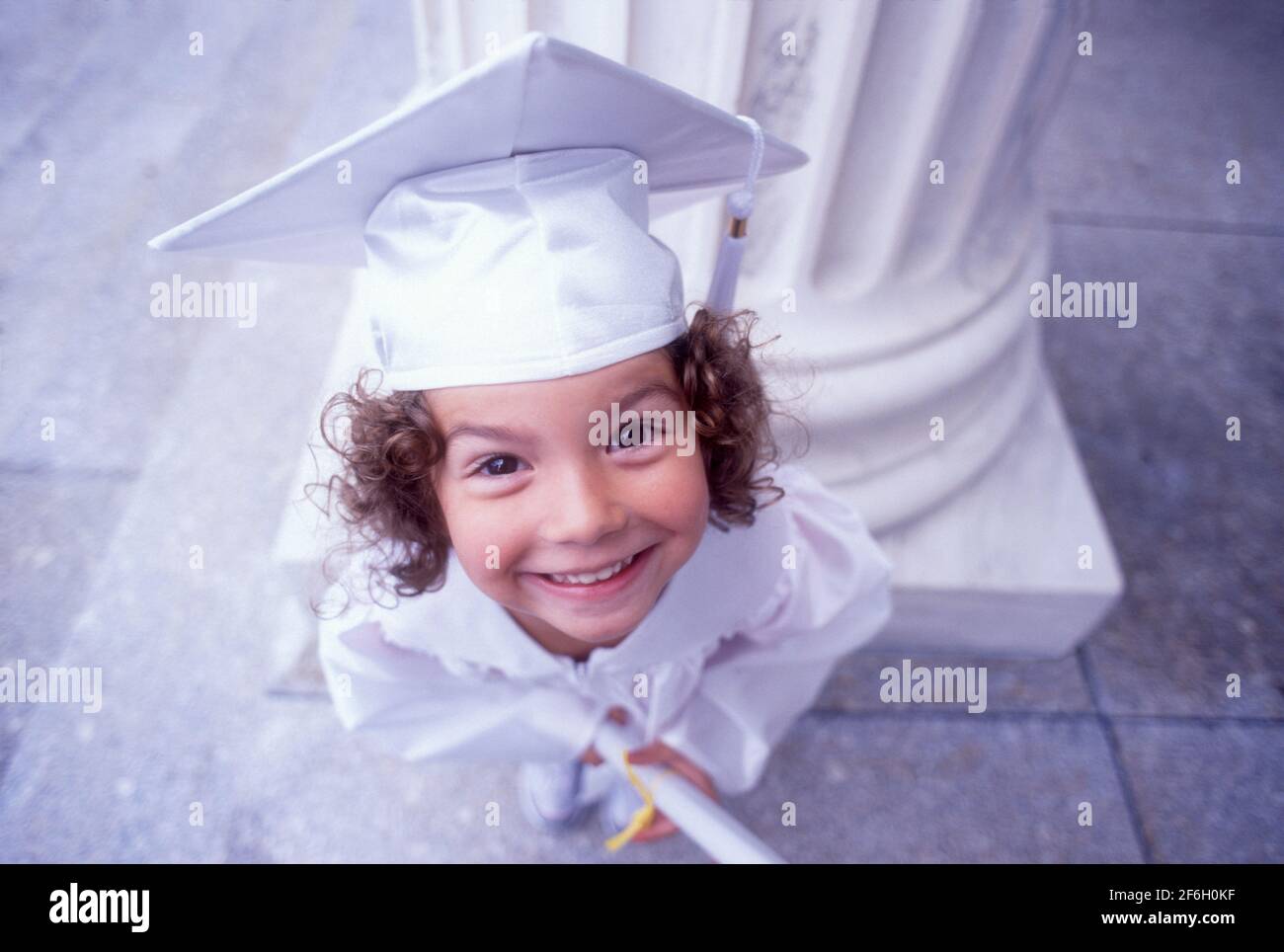Portrait de fille (4-5) en chapeau blanc de graduation et robe Banque D'Images