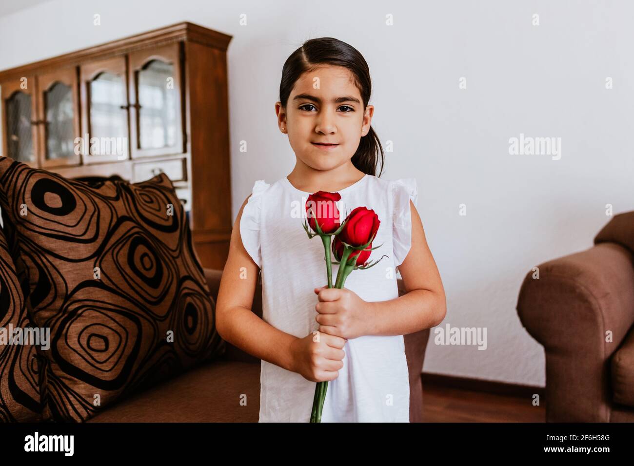 petite fille latine félicite maman et donne ses fleurs Pour une heureuse fête de mère à la maison dans la ville de Mexico Banque D'Images