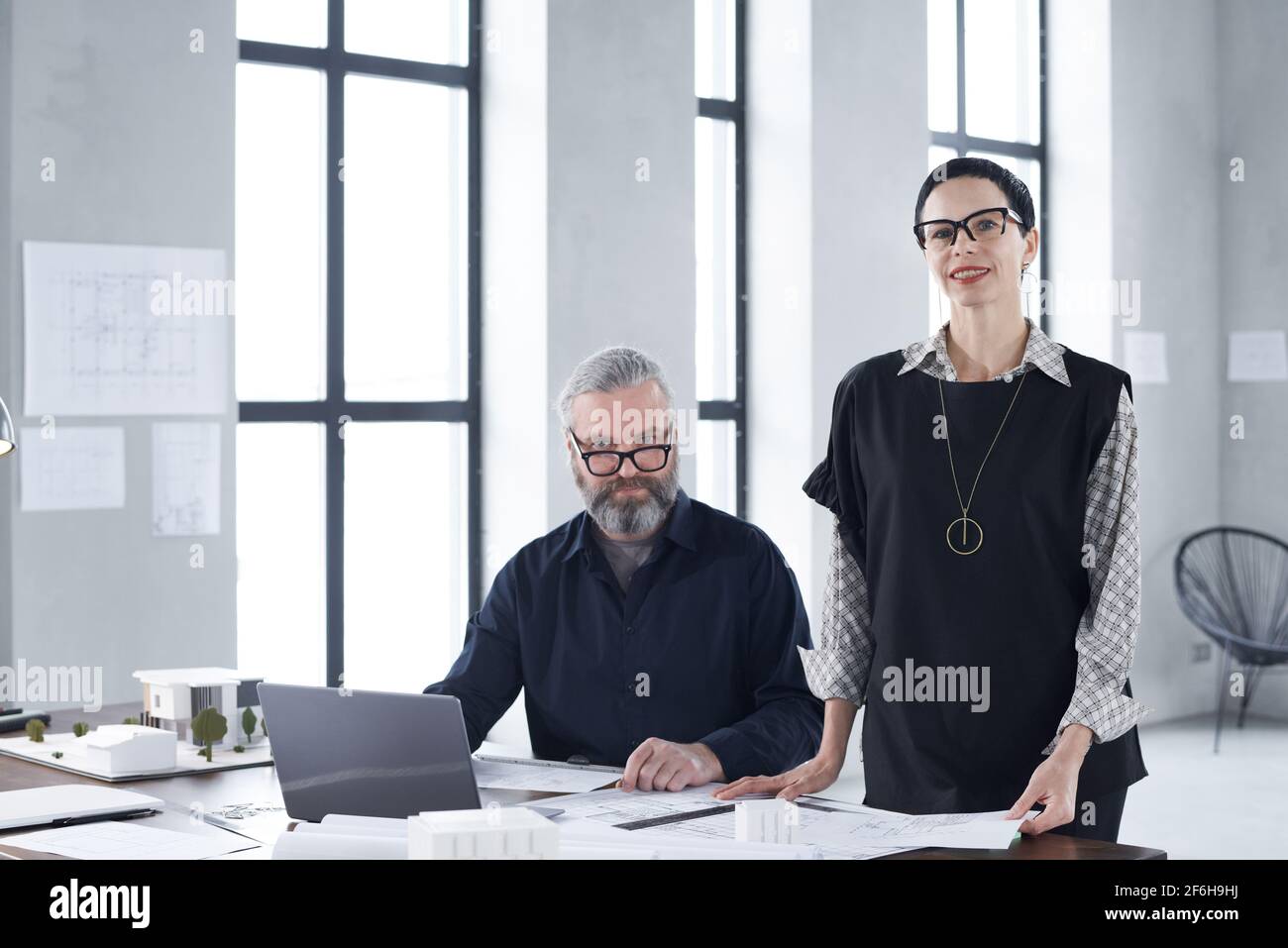 Portrait de personnes d'affaires mûres souriant à l'appareil photo tout en travaillant ensemble dans un bureau moderne Banque D'Images