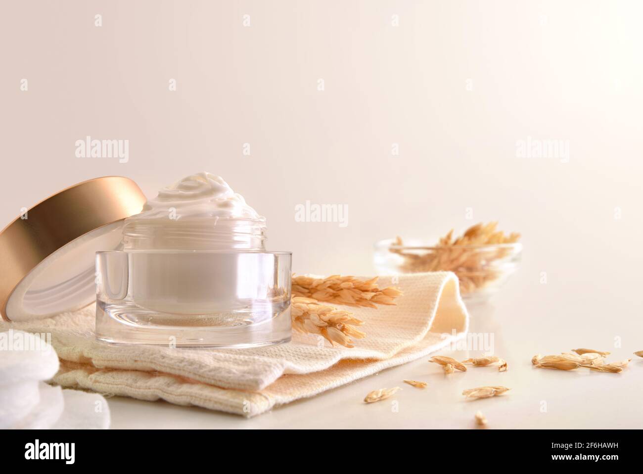 Crème hydratante pour le visage d'avoine dans un pot en verre avec des pointes sur la table blanche pour le traitement de l'acné. Vue avant. Composition horizontale. Banque D'Images