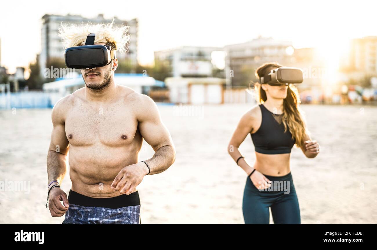 Jeune couple qui court à la plage avec un casque de masque de réalité virtuelle - Sport et concept de technologie avec des amis jogging et exercice Banque D'Images
