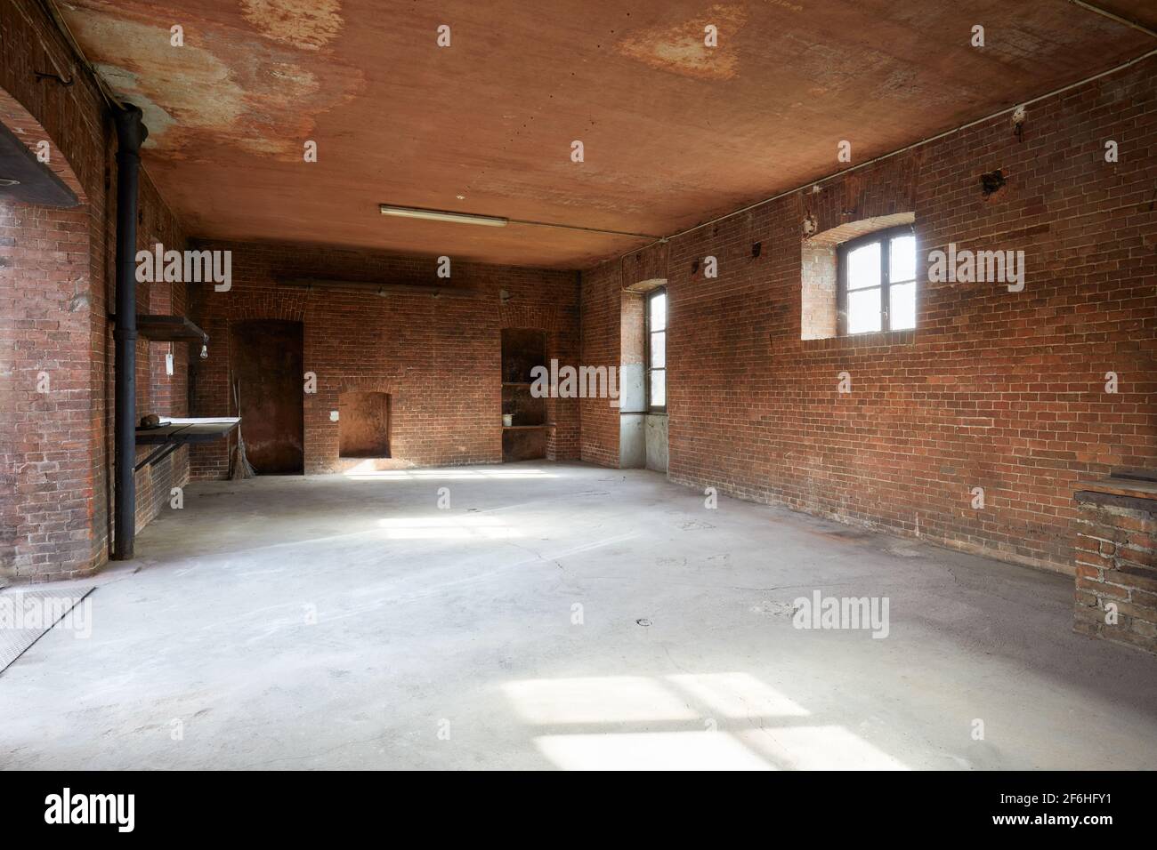 Intérieur ancien et vide de l'atelier avec murs en briques rouges, lumière du soleil Banque D'Images