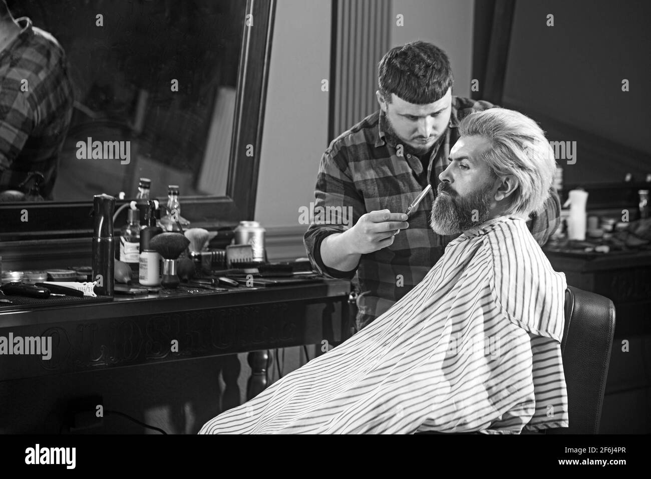 Homme blond brutal ayant une coupe de cheveux au salon de coiffure. Coiffeur mains faisant la coiffure Banque D'Images