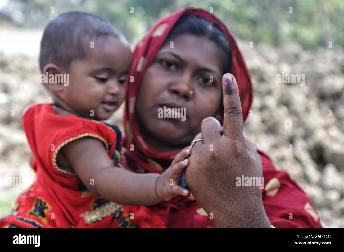 Une femme avec son enfant montre son doigt inked après avoir voté à East Midnapur.les électeurs de Nandigram ont voté lors de la deuxième phase des élections de l'Assemblée du Bengale occidental sous le déploiement de forces centrales armées lourdes pour rendre les élections pacifiques. Banque D'Images