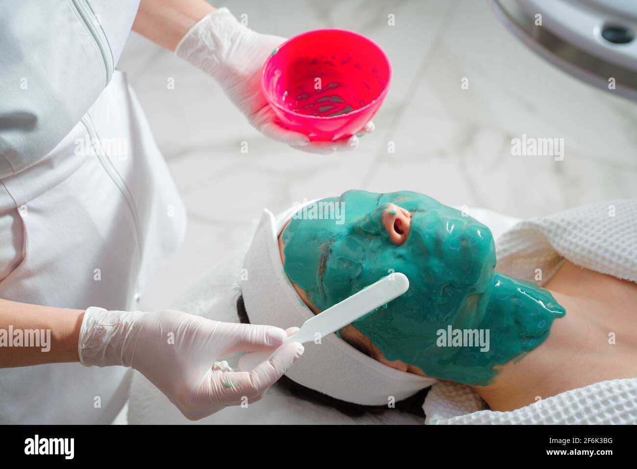 Soin du visage. Un masque est appliqué au visage d'une femme dans une clinique de cosmétologie. Gros plan Banque D'Images