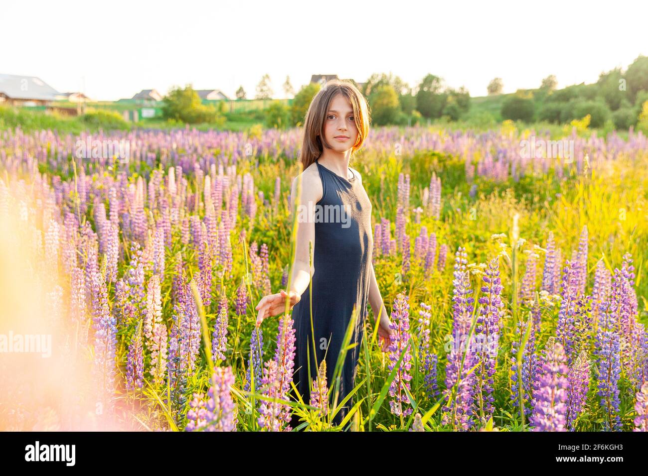 Bonne adolescente souriante à l'extérieur. Belle jeune femme de l'adolescence se reposant sur le terrain d'été avec fleurs sauvages fleur de fond vert. T-shirt enfant gratuit Banque D'Images