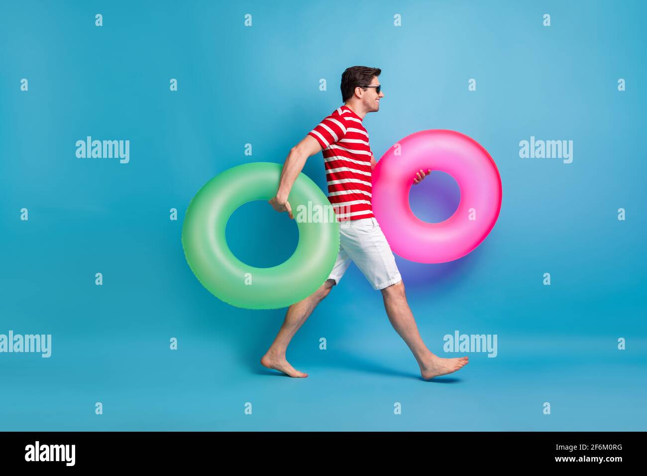 Pleine longueur de corps photo homme allant nager dans la mer isolation des cercles en caoutchouc sur un arrière-plan bleu vif Banque D'Images