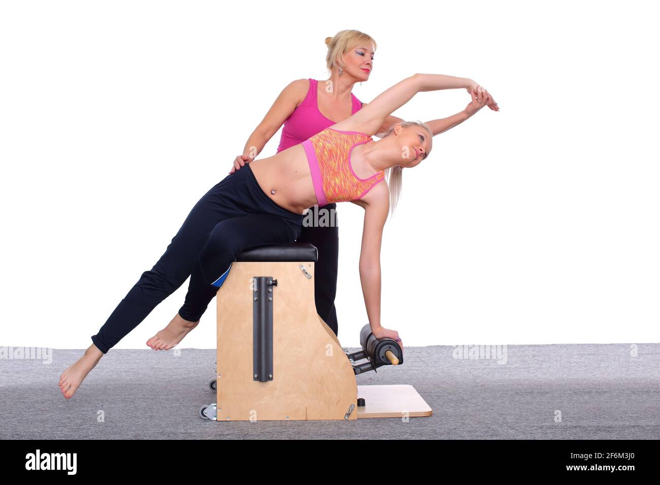Un entraîneur de 50 ans enseigne un exercice de pilates à une jeune fille  de chaise d'ascenseur, qui arque son corps. Elle est assise sur une  béquille légère Photo Stock - Alamy
