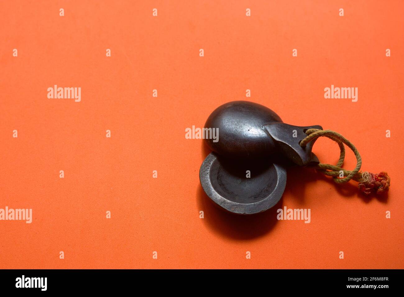Gros plan de quelques castanets traditionnels en bois sombre de musique espagnole sur fond orange avec espace de copie Banque D'Images