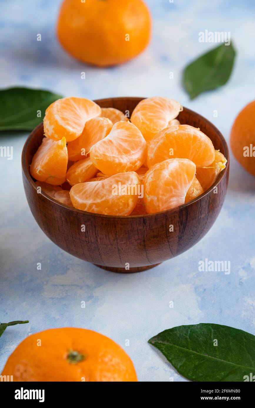 Les tranches de mandarine de Clémentine dans un bol en bois sur fond bleu Banque D'Images