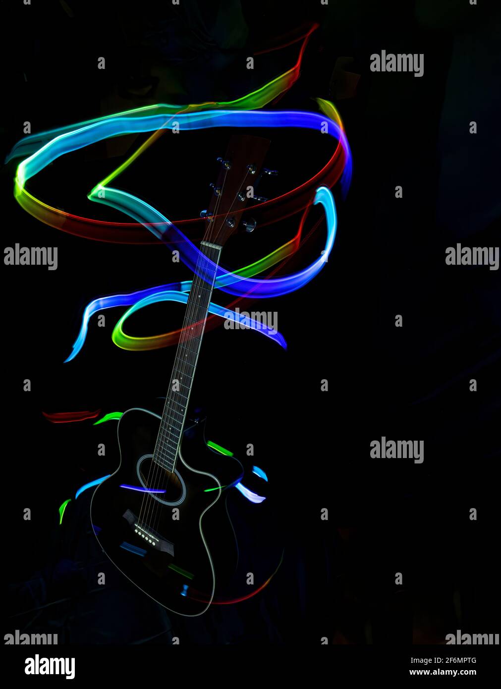 silhouette d'une guitare acoustique dans le noir illuminée de traces de lumière colorée, peinture avec lumière, lumières colorées, longue exposition, verticale Banque D'Images