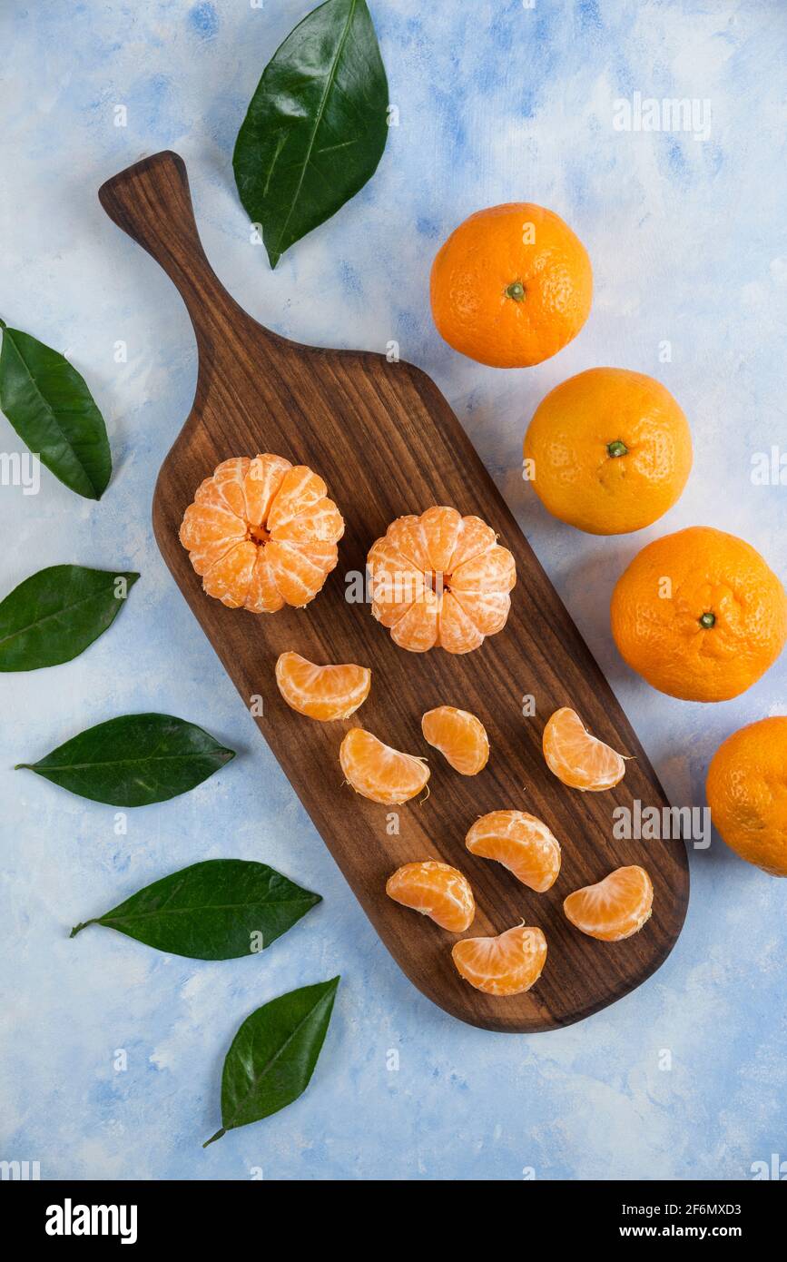 Tranches de mandarines fraîches pelées sur bois avec des mandarines entières Banque D'Images