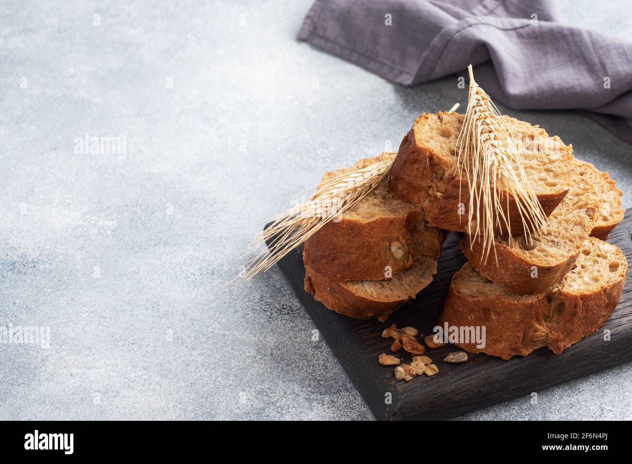 Baguette de seigle tranché sur fond gris avec céréales. Pain de grain entier, un concept alimentaire sain. Copier l'espace Banque D'Images Baguette de seigle tranché sur fond gris avec céréales. Pain de grain entier, un concept alimentaire sain. Copier l'espace Banque D'Images