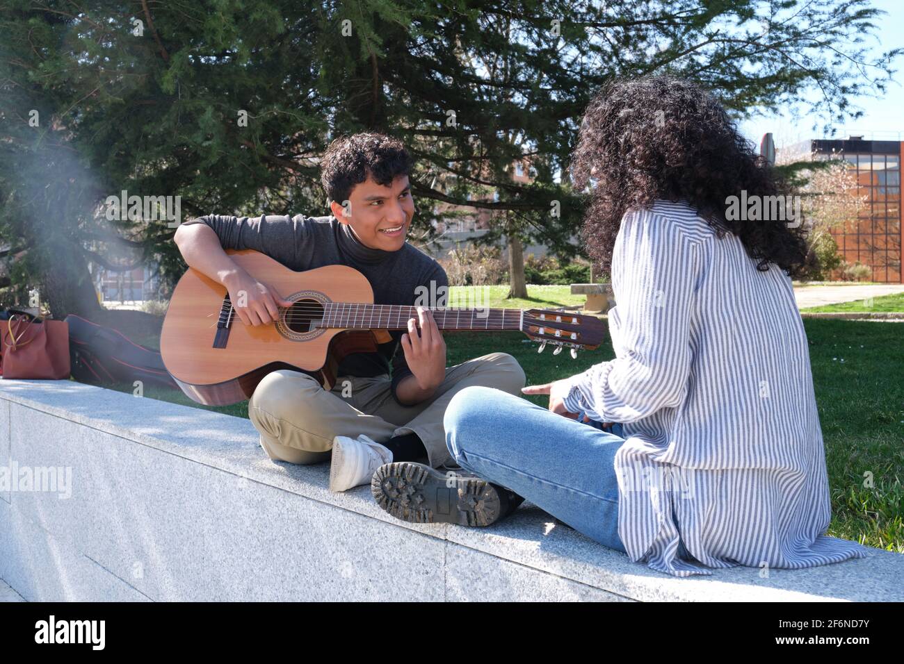 Jeune couple latin jouant de la guitare sur le campus universitaire. Vie  universitaire, génération du millénaire Photo Stock - Alamy