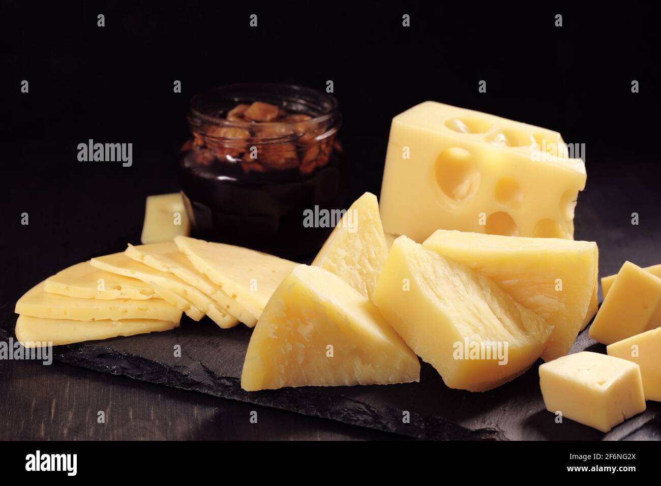 différents types de fromage coupés en tranches se trouvent sur la pierre assiette avec miel et noyer Banque D'Images