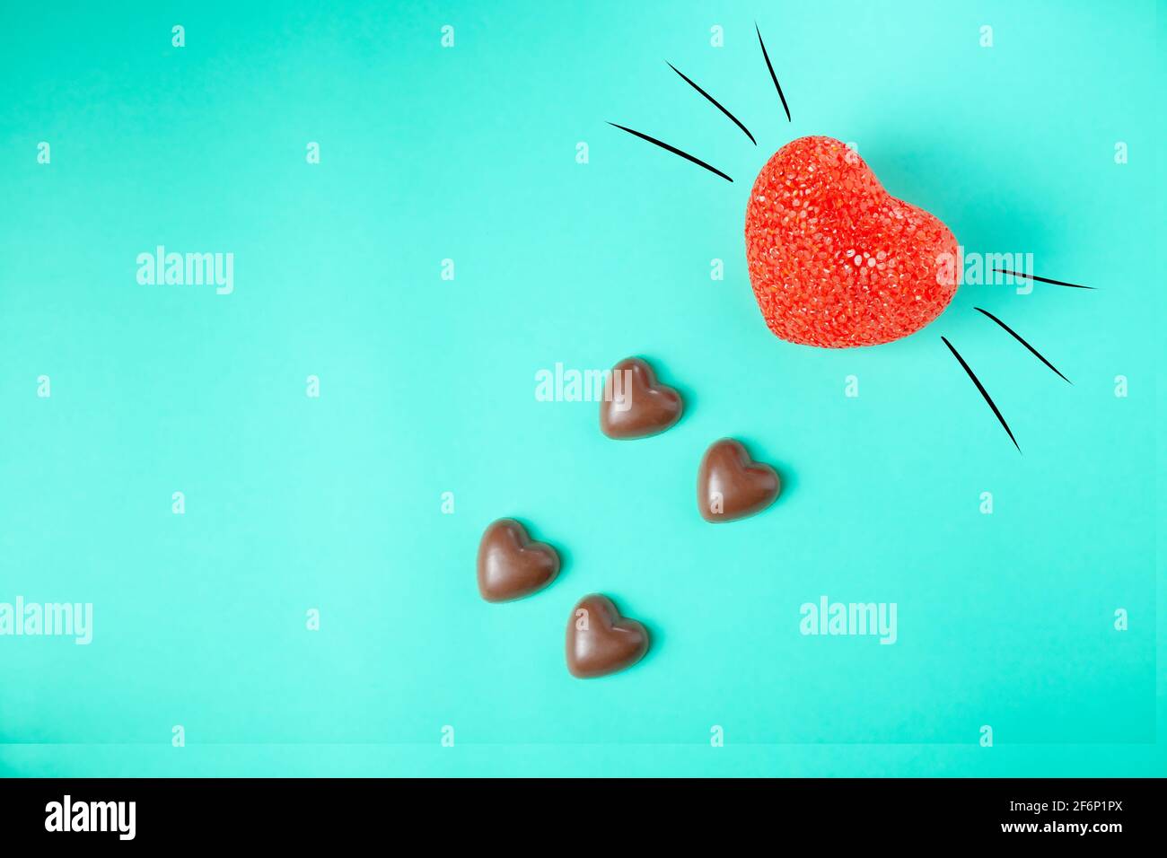 les coeurs en chocolat ressemblent à des empreintes de chat sur fond turquoise, en gros plan. concept. les pattes de chat en chocolat sont imprimées avec le nez rouge et la moustache bott des chats Banque D'Images
