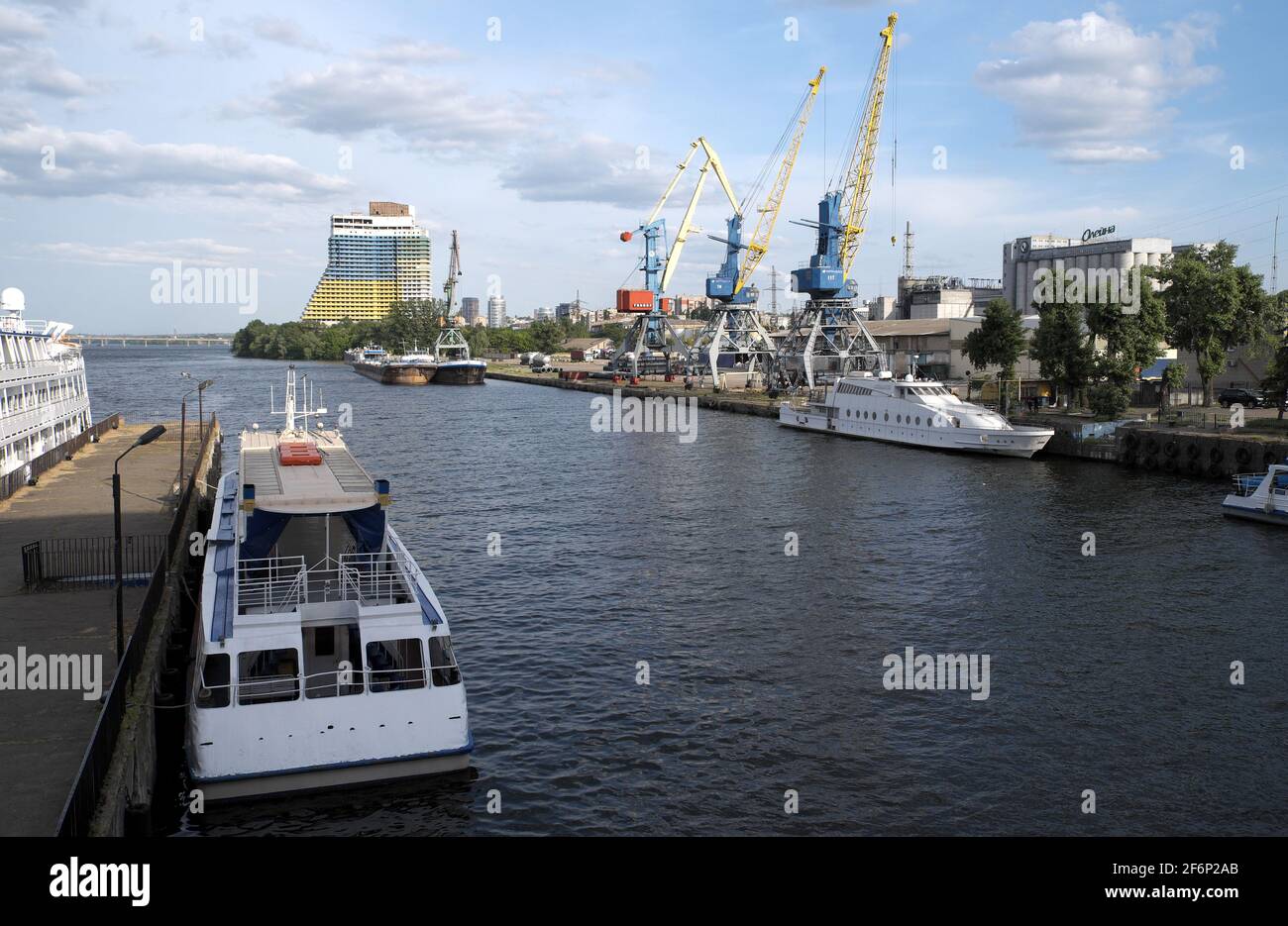 Bateaux de croisière amarrés à côté du quai, avec des grues et un immeuble au-delà, rivière Dnieper, Dnipro, Ukraine. Banque D'Images