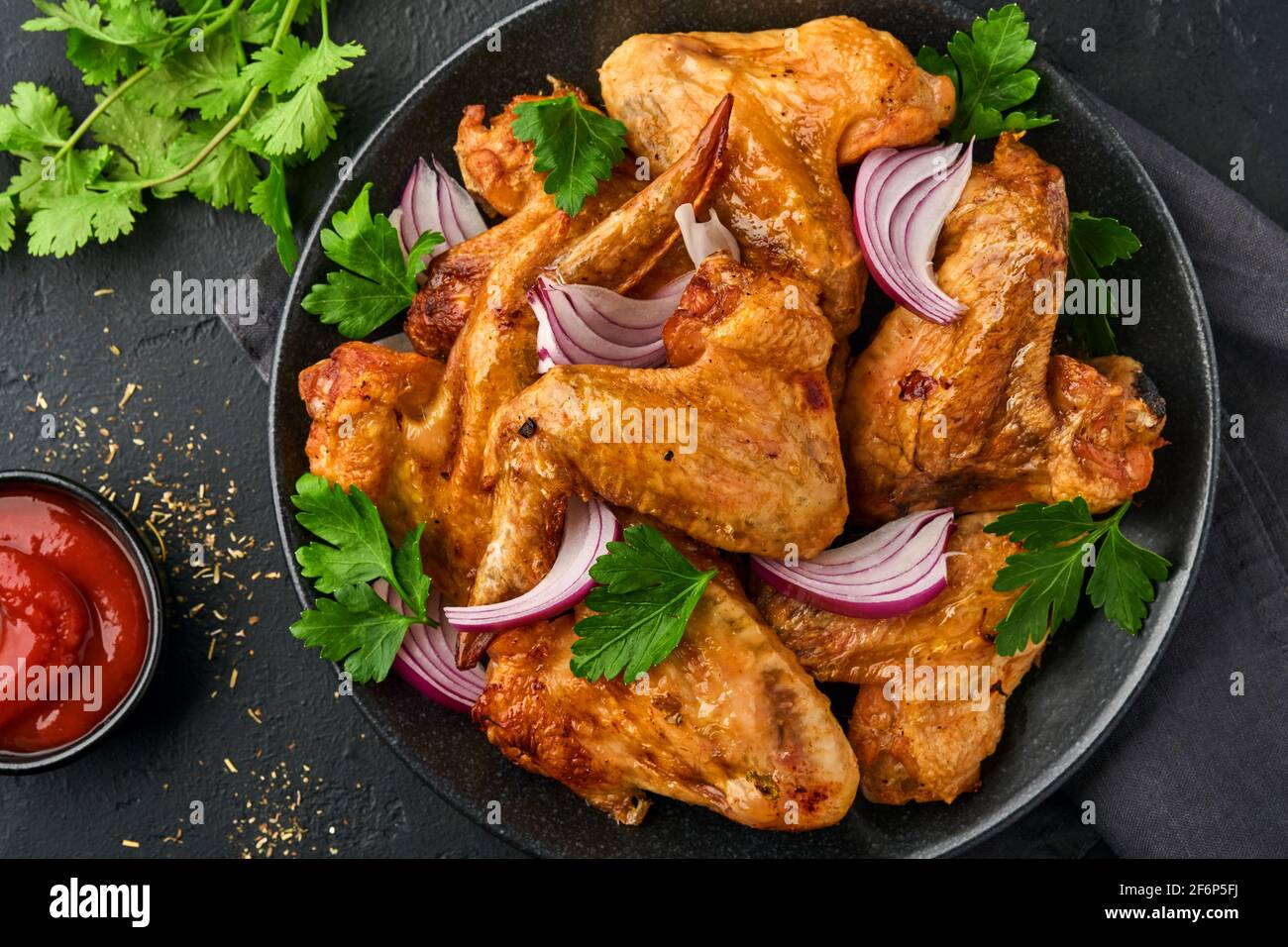 Ailes de poulet grillées ou barbecue grillé avec épices et sauce tomate salsa sur une assiette noire. Vue de dessus avec espace de copie. Banque D'Images