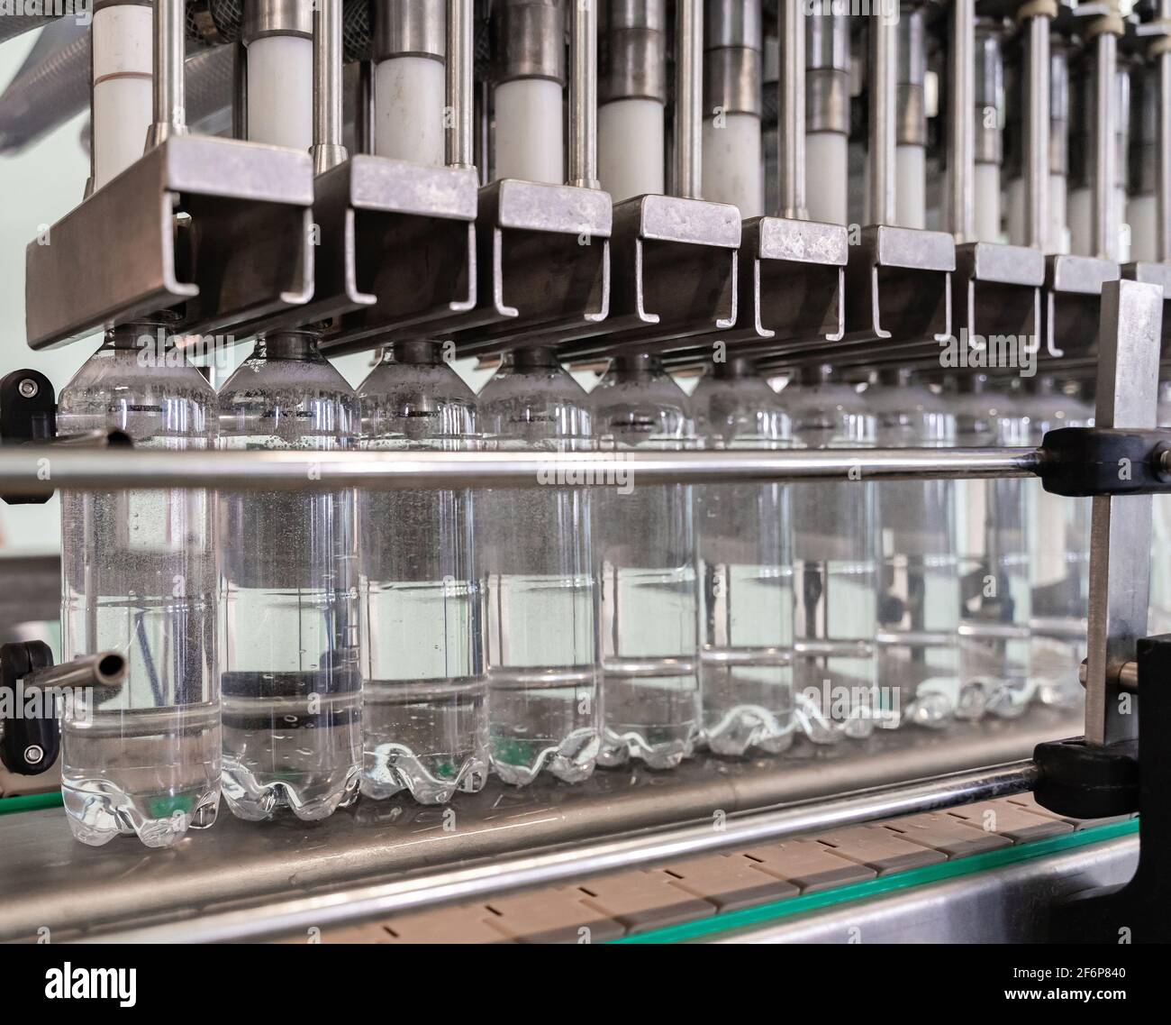 La machine verse de l'eau dans des bouteilles en plastique. Chaîne de production. Banque D'Images