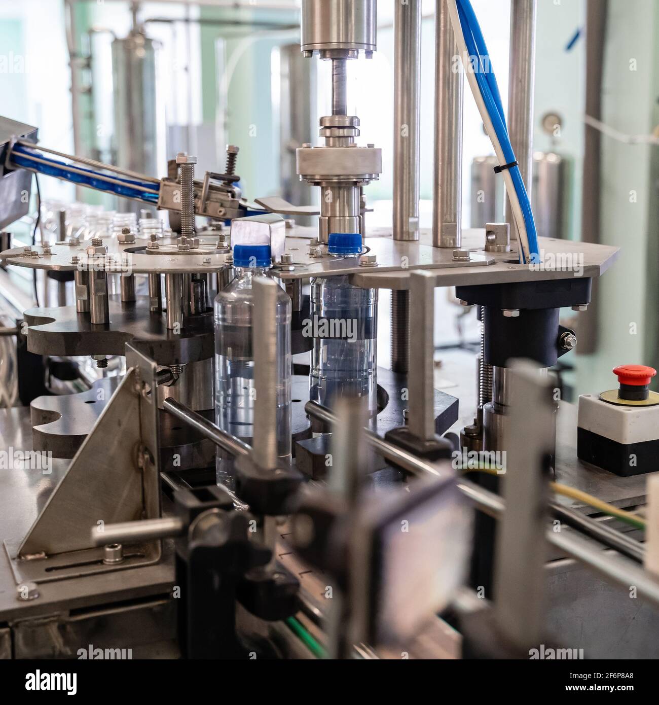 La machine serre les couvercles sur les bouteilles en plastique. Chaîne de production d'eau. Banque D'Images