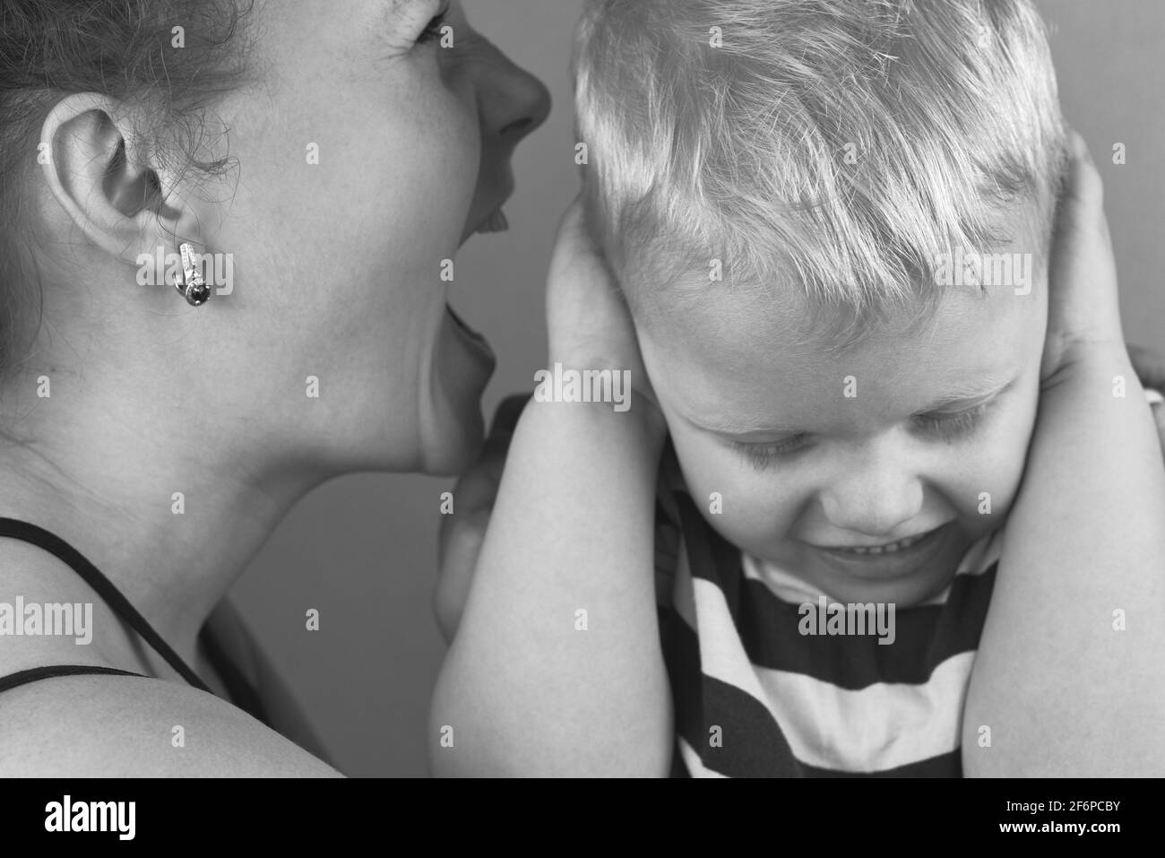 Le petit garçon couvre ses oreilles avec ses mains tandis que la mère en colère hurle à lui, noir et blanc photo. Banque D'Images