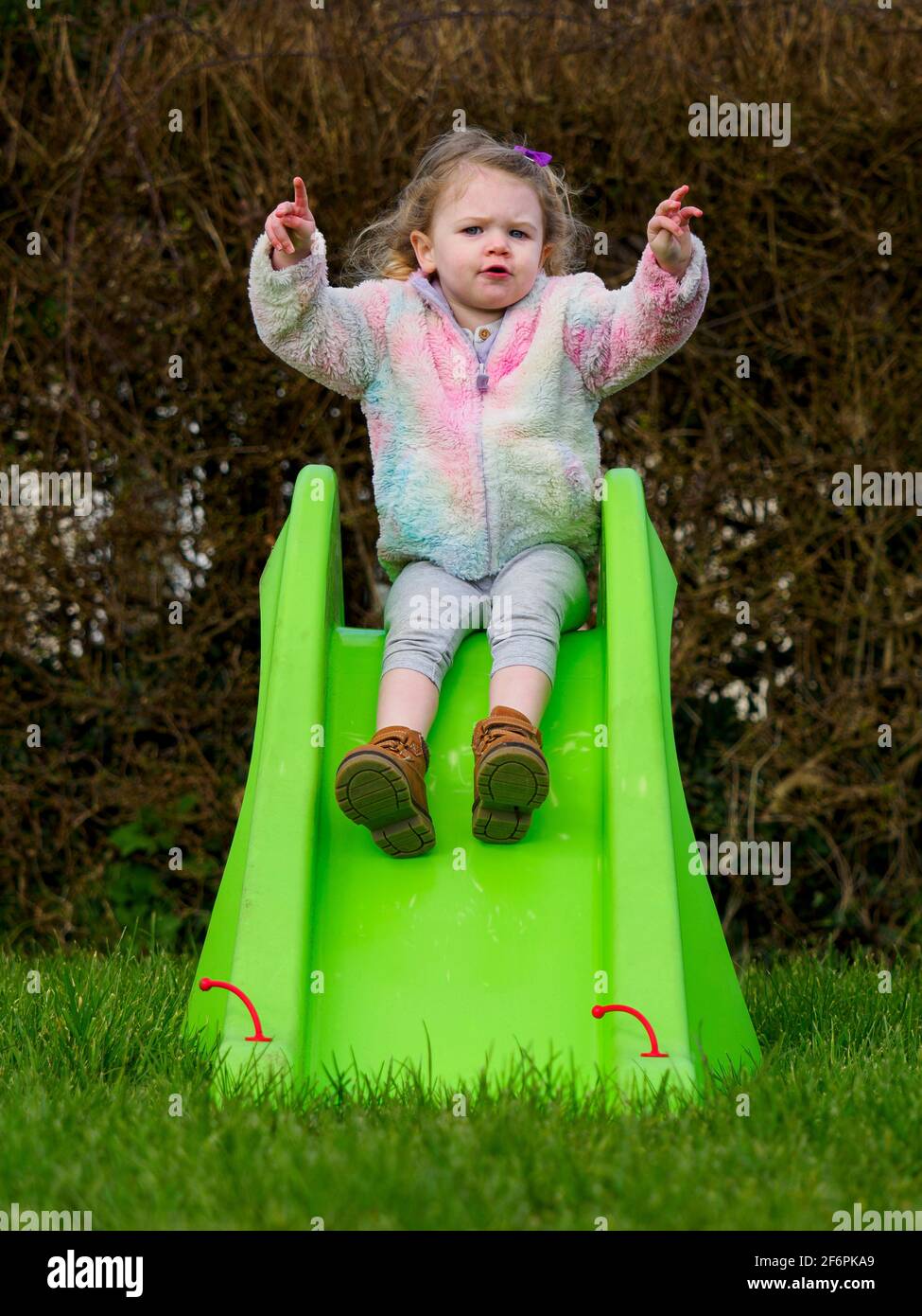 Tout-petit s'est assis sur un toboggan de jardin, au Royaume-Uni Banque D'Images