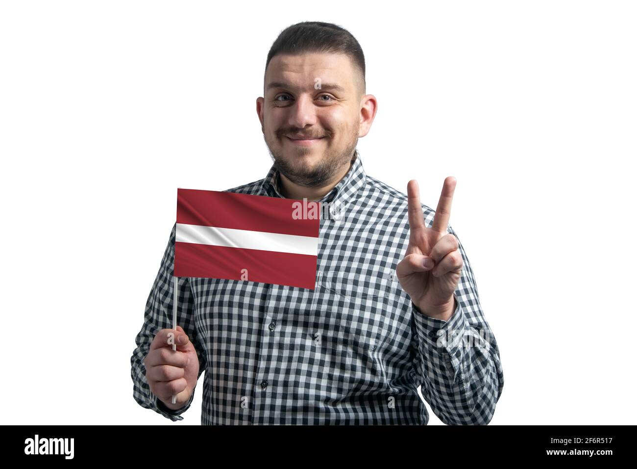 Homme blanc tenant un drapeau de la Lettonie et montre deux doigts isolés sur un fond blanc. Banque D'Images
