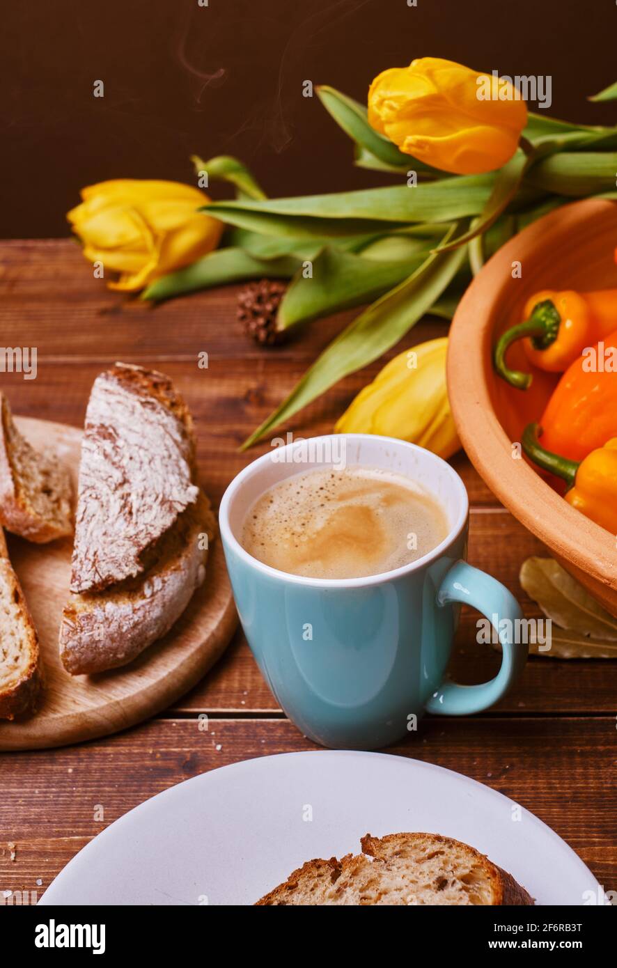 table rustique, avec un éclairage chaleureux et confortable montre tasse avec café, cannelle, sur la table vous pouvez également voir des poivrons et un grand bol en céramique dans la couleur crue Banque D'Images