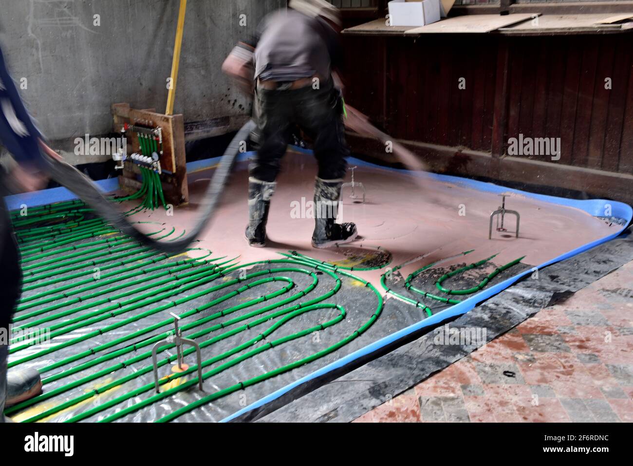 Workman versant une table auto-nivelante anhydrite pompée sur le plancher hydronique tuyau de chauffage Banque D'Images