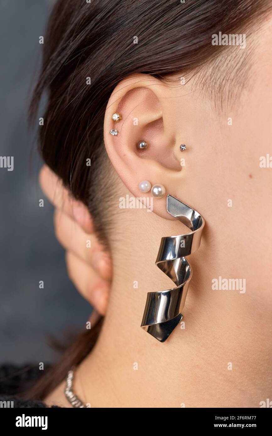 Boucle d'oreille cloutée au cerf sur l'oreille de la femme gros plan. Perçage Banque D'Images