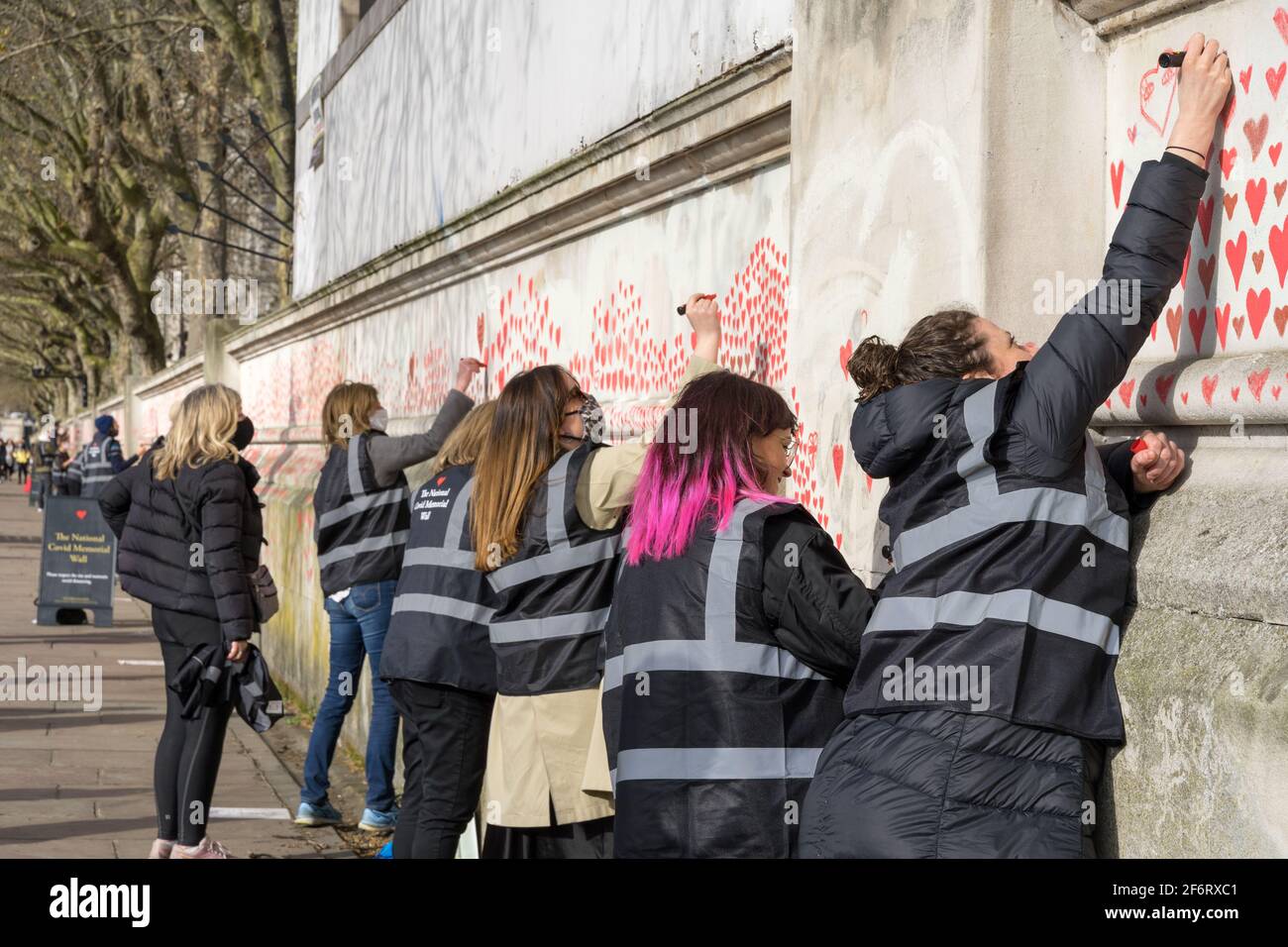 Les étudiants, les touristes, les amis et la famille , les bénévoles peignent des coeurs rouges sur le mur national du mémorial des Covid, rive sud de Londres, Angleterre Banque D'Images