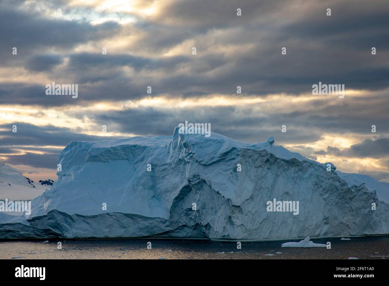 Les rayons chauds du soleil à travers la couverture nuageuse créent une belle lumière sur l'iceberg près du pôle Sud. Banque D'Images