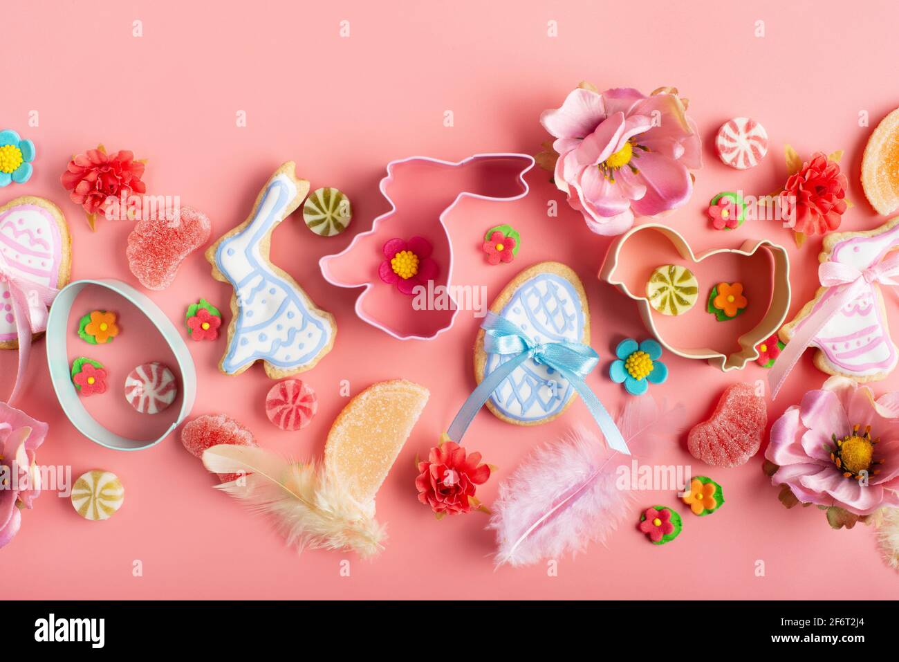 Biscuits givrés de Pâques en forme de poulet à l'œuf et de lapin, saupoudrés de sucre, bonbons, emporte-pièces sur fond rose. Maquette de pose à plat. Banque D'Images