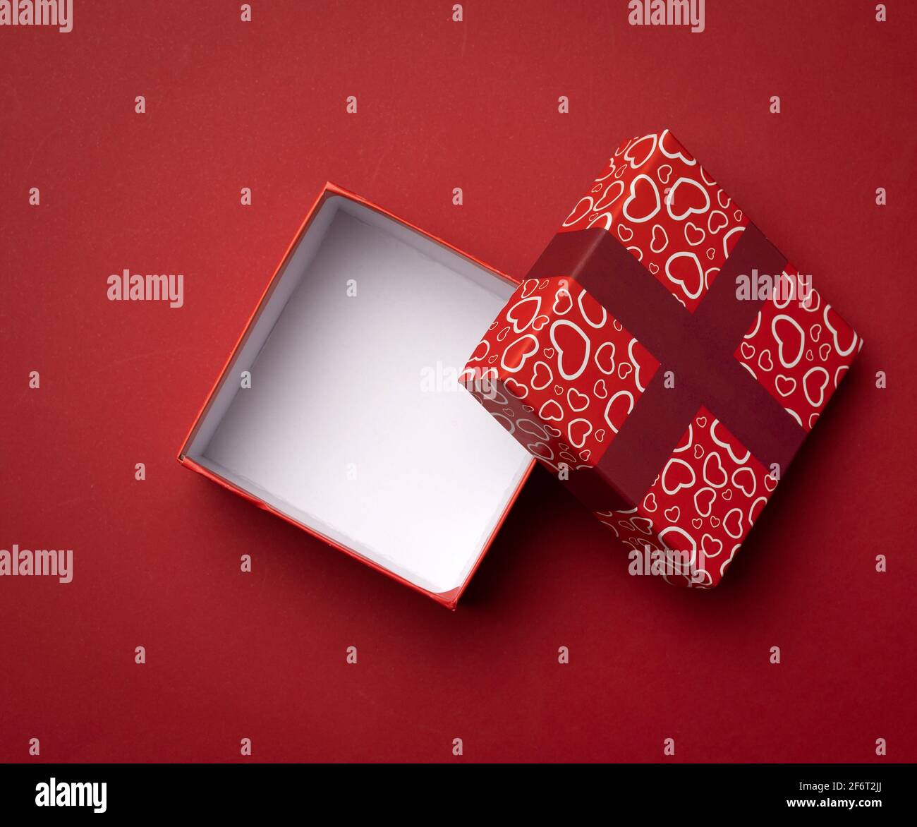 boîte rouge carrée vide sur fond rouge, cadeau ouvert, vue du dessus. Banque D'Images