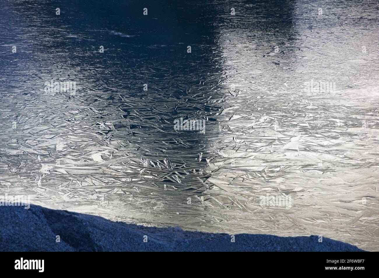 réflexion de roches ensoleillées sur des cristaux de glace sur une alpine lac dans les montagnes de la Sierra Nevada Banque D'Images