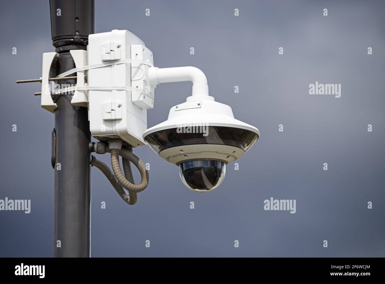 caméra de surveillance dans un parc monté sur un poteau lumineux avec fond ciel gris Banque D'Images